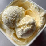 Scoop van romig vanille-ijs in een kom met een lepel